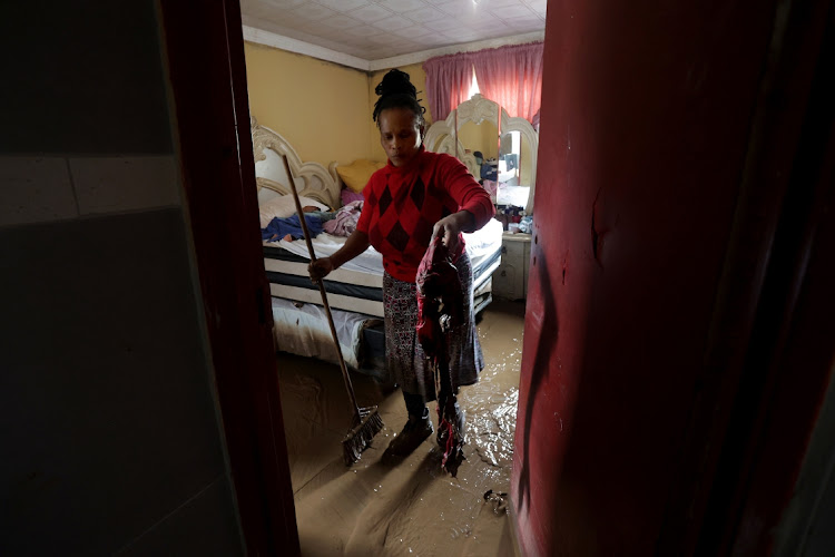 Bongiwe Zuma, 39, tries to mop up and remove water after rain flooded Peace Valley, Pietermaritzburg.