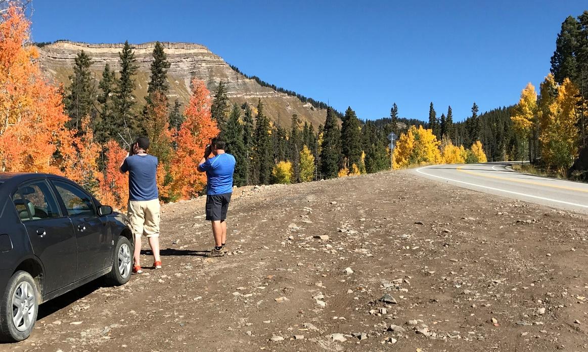 Pedestrians pulled over on the side of the road taking pictures of fall colors