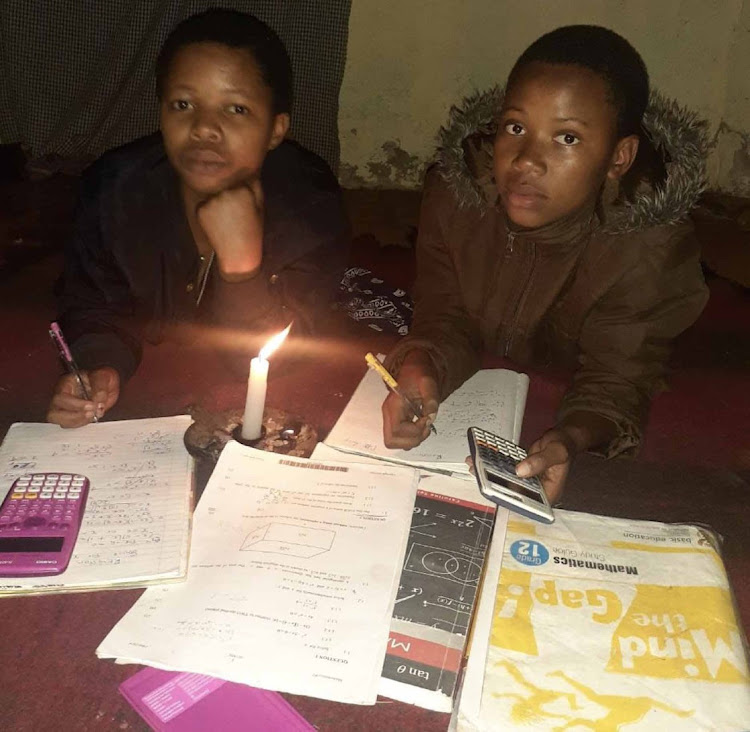 Grade 12 pupil Phindile Tshaka and neighbour Nelisiwe Momadzoyiya sue a candle to catch up on school work.