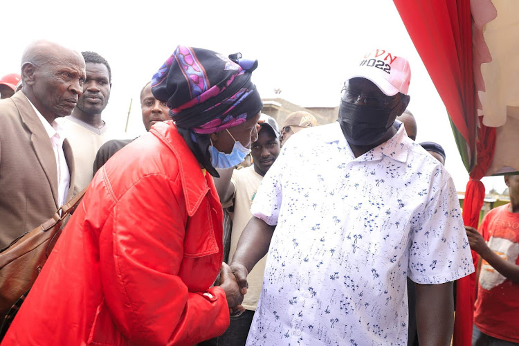 Kiambu Governor James Nyoro greets an elderly lady at Gikambura village on Tuesday.