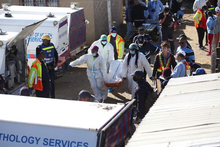 Pathology department workers carry bodies from the tavern. The Eastern Cape government says there will be a mass funeral service for all the victims next Wednesday.