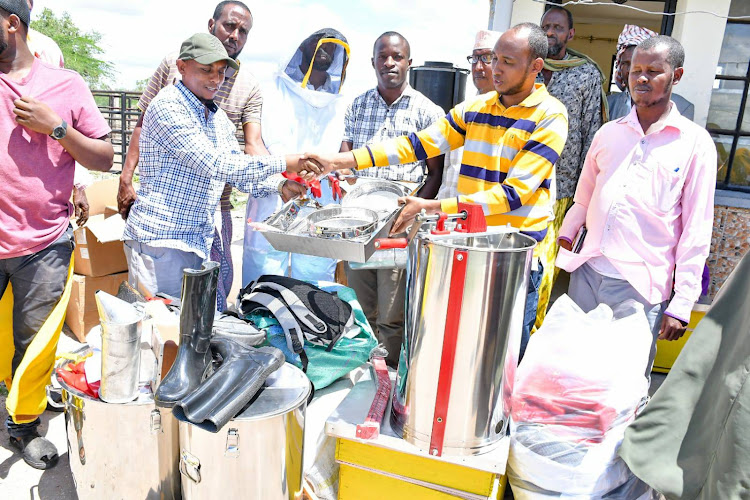 Abdullahi Dahir, the Business Development Specialist officer from LMS hands over the equipment to the Sacco chairman Abdullahi Abdi at Masalani town in Garissa on Sunday, May 8.