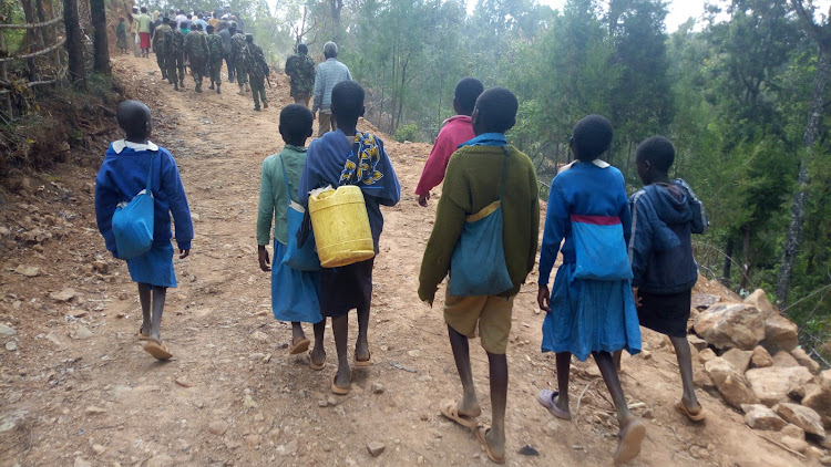 Schoolchildren and residents of Kitibei walk past Korokorwonin-Kitibei access road