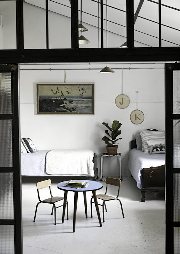 Jacob and Kranhold's bedroom has a subtle blue theme. The couple inherited the beds from Tina's family. The table and chairs are from Hannes's childhood and the pendants are from a former dairy that sells pieces from local farms and factories.