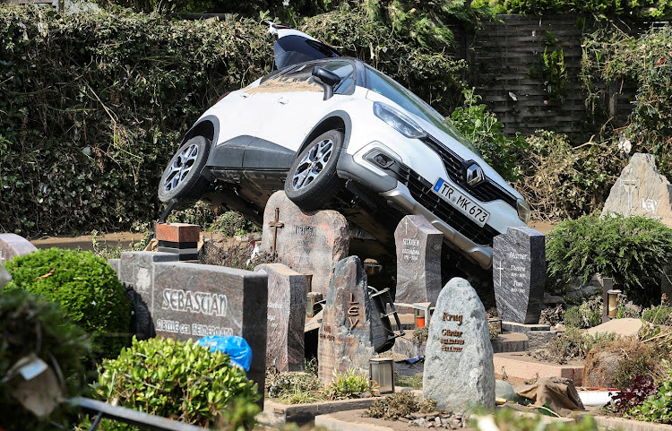 A car leans on graves at a cemetery after heavy rainfalls in Dernau, Germany.