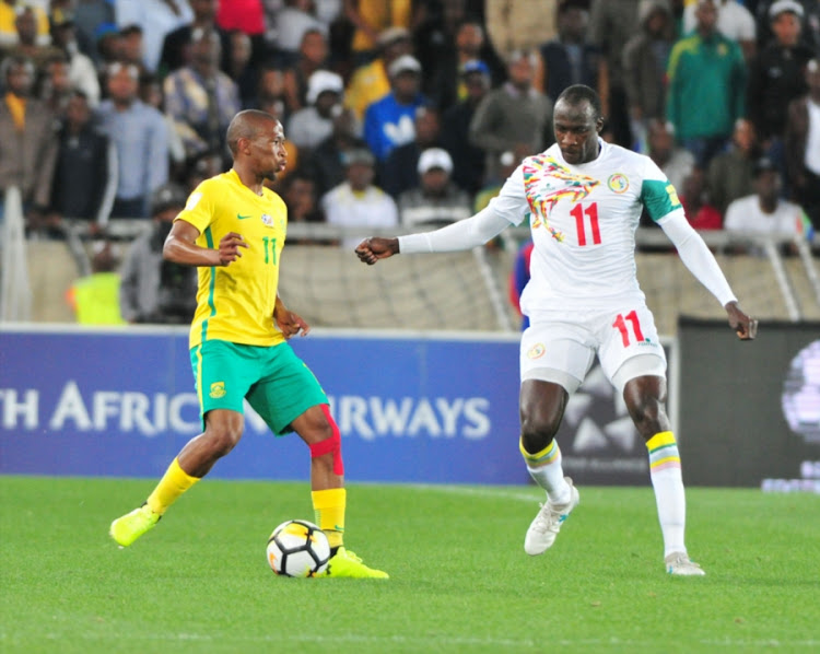 England-based SA midfielder Kamohelo Mokotjo protects the ball under the guard of Cheikh Ndoye during the 2018 FIFA World Cu qualifier match between Bafana Bafana and Senegal at Peter Mokaba Stadium in Polokwane on November 10, 2017.