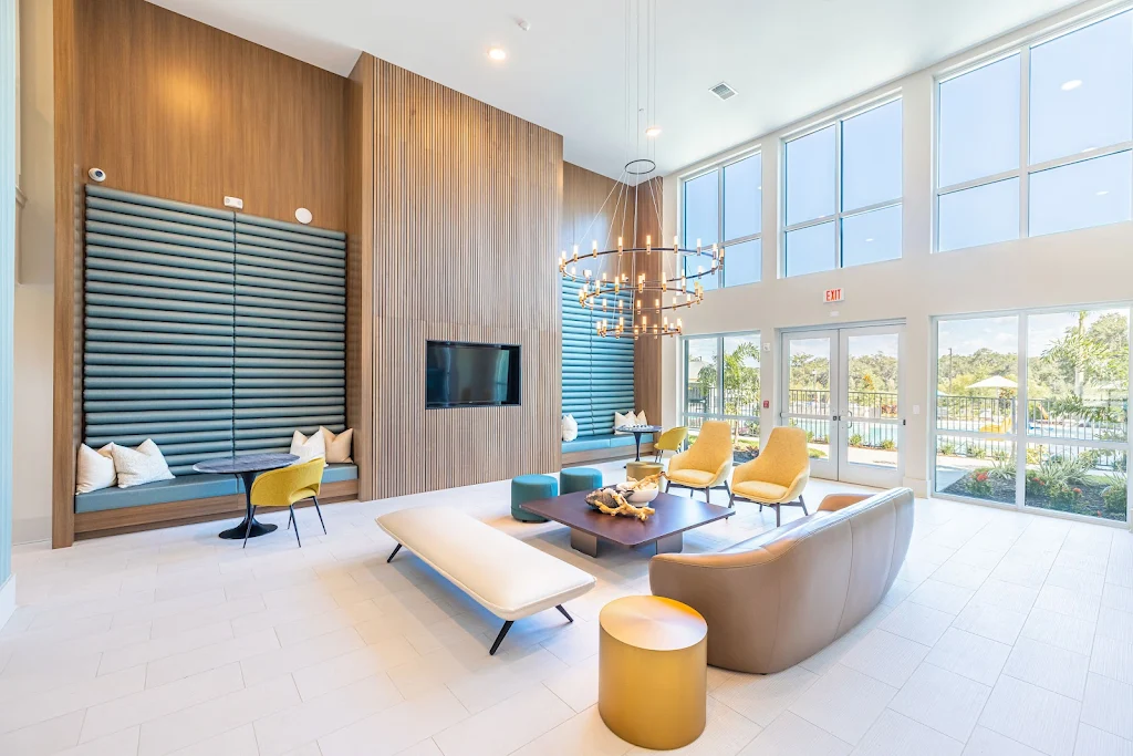 Clubhouse seating area with expansive ceilings, high-end furniture, mounted tv, and floor to ceiling windows.