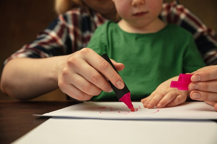 A young child's hands holding colorful markers engaged in creative activities at home.