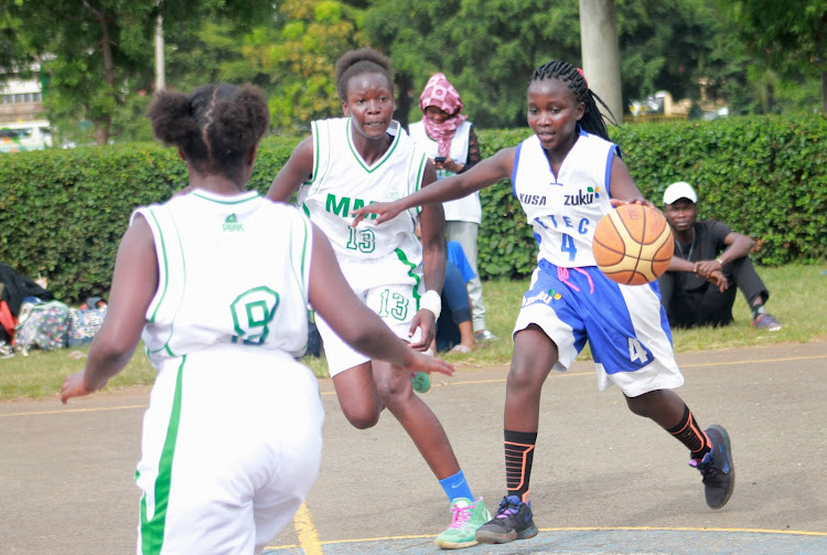 Zetech University's Naomi Bosibori (R) dribbles the ball past Multimedia University's Frida Kandie (13) and Beatrice Murage in past match