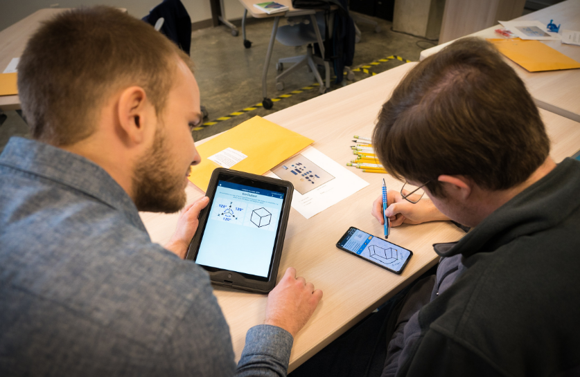 a teacher and a student working with a tablet and a smartphone at a table