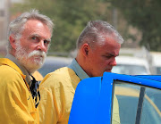 Jim Fitton from Britain and Volker Waldmann from Germany, who are suspected of smuggling ancient artefacts out of Iraq, are escorted in handcuffs by Iraqi policemen, outside a court in Baghdad, Iraq, May 22, 2022. 