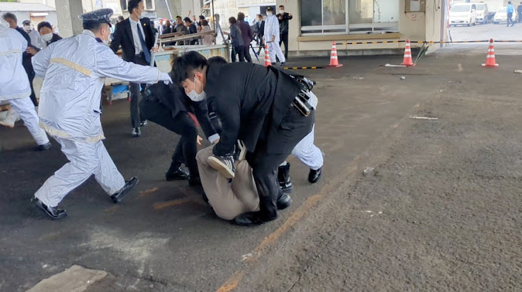 Law enforcement personnel hold a person to ground after an explosion was heard near Japanese Prime Minister Fumio Kishida's outdoor speech, in Saikazaki, Wakayama prefecture, Japan, on April 15 2023 in this screen grab obtained from a social media video. Picture: TWITTER @Ak2364N via REUTERS