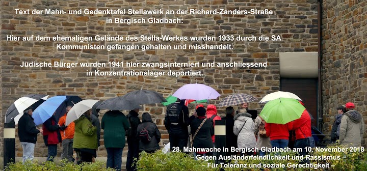 Menschen mit Regenschirmen vor Kirchenmauer. Eingefügter Text: «28. Mahnwache in Bergisch Gladbach. Gegen Ausländerfeindlichkeit und Rassismus Für Toleranz und soziale Gerechtigkeit. Text der Mahn- und Gedenktafel Stellawerk an der Richard-Zander-Straße in Bergisch Gladbach: ‹Hier auf dem ehemaligen Gelände des Stellawerkes wurden 1933 durch die SA Kommunisten gefangen gehalten und misshandelt. Jüdische Bürger wurden 1941 hier zwangsinterniert und anschließend in Konzentrationslager deportiert.›».