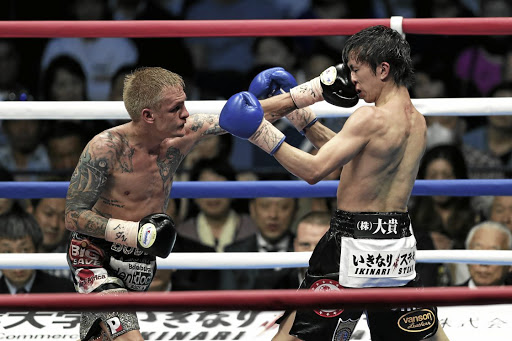 Challenger Hekkie Budler of SA, left, punches champion Ryoichi Taguchi on his way to the IBF and WBA light flyweight titles at Ota City General Gymnasium in Tokyo, Japan in May./Kiyoshi Ota / Getty Images