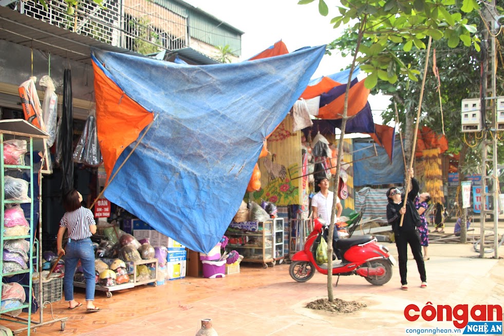 Khi thấy lực lượng giải tỏa đến, nhiều hộ kinh doanh bắt đầu tháo dỡ các tấm bạt trên hành lang đường bộ