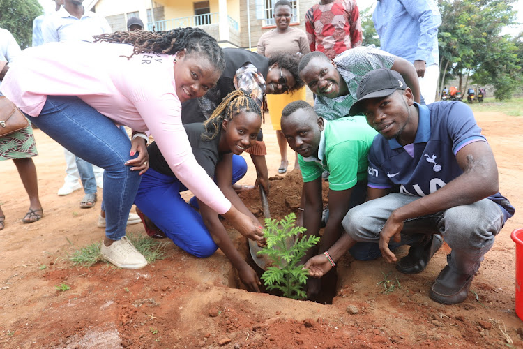 Youth pose for a photo as they plant a tree at the Kitui South sub-county administrator's office compound on Friday