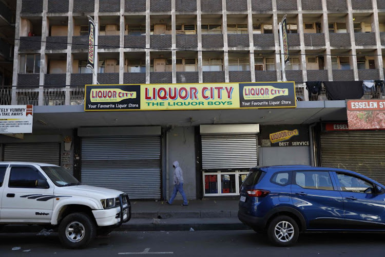 A man walks past a closed liquor shop in Hillbrow, Johannesburg, on Monday after President Cyril Ramaphosa on Sunday re-imposed a night curfew and suspended alcohol sales as Covid-19 threatens to overwhelm the health system