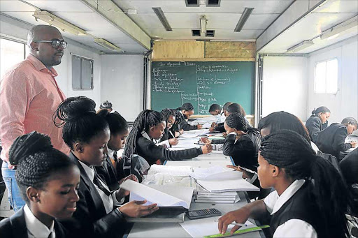 RISING ABOVE: Grade 12 maths and physics learners from Ulwazi secondary school in Mdantsane use a bus as a classroom – and still manage to be one of the highest performing schools in the province Picture: SIBONGILE NGALWA