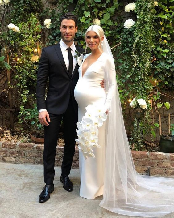 A groom and his bride who is wearing a maternity wedding dress