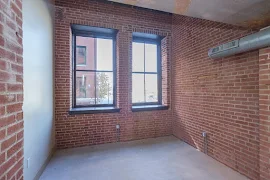 Living area with brick walls and two black framed windows