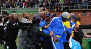 Mamelodi Sundowns coach Pitso Mosimane at the centre of scuffle broke broke out between Mosimane and the head of the security company (not in this picture) that does duty for AmaZulu FC's home matches following an Absa Premiership match at King Zwelithini Stadium in Umlazi, Durban, on Sunday September 16 2018. Sundowns' team manager Peter Ndlovu (wearing a red tie) is seen trying to pull the coach away. 
