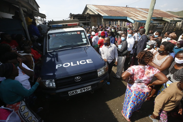 Police remove the body of Martha Waithera who was killed by her lover on Monday night as residents mill around the scene.