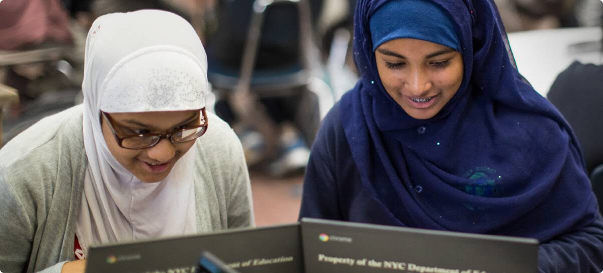 Twee studenten in sluier die op een Chromebook werken