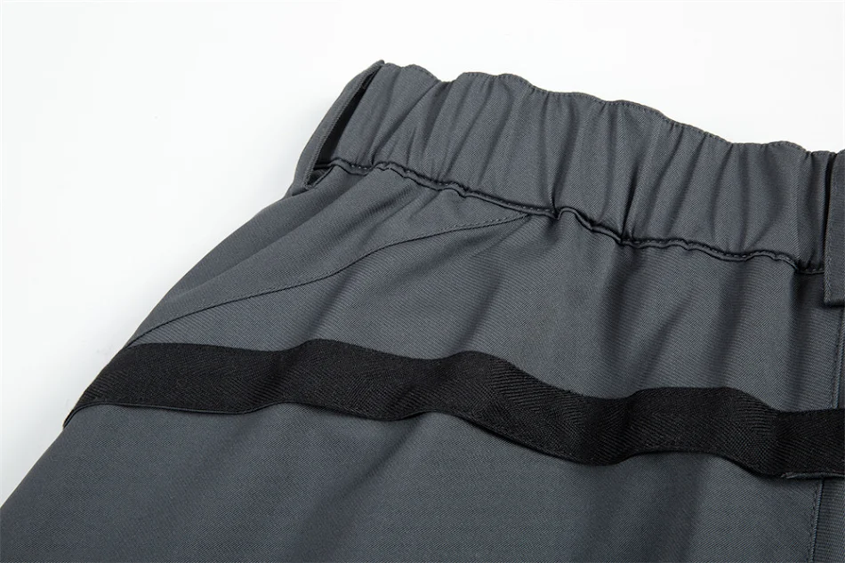 Pantalon décontracté homme à genouillères plissées, décorations zippées, chevilles à bande, pour un look tendance et confortable.