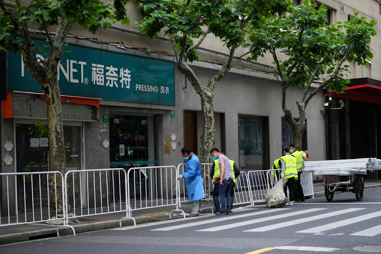 Workers set up barriers to seal off an area during lockdown, amid the Covid-19 pandemic, in Shanghai, China, on May 16 2022. Picture: REUTERS/ALY SONG