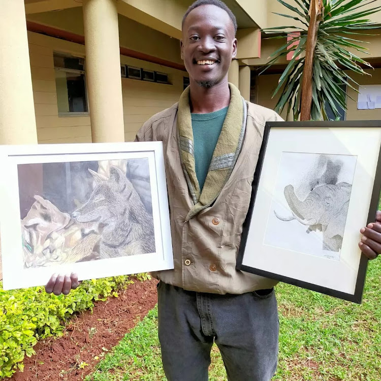 Artist Antony Odhiambo poses for a photo holding pieces of art he has drawn.