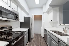 Galley kitchen with white upper and grey lower cabinets, white quartz countertops, stainless steel appliances, wood floors