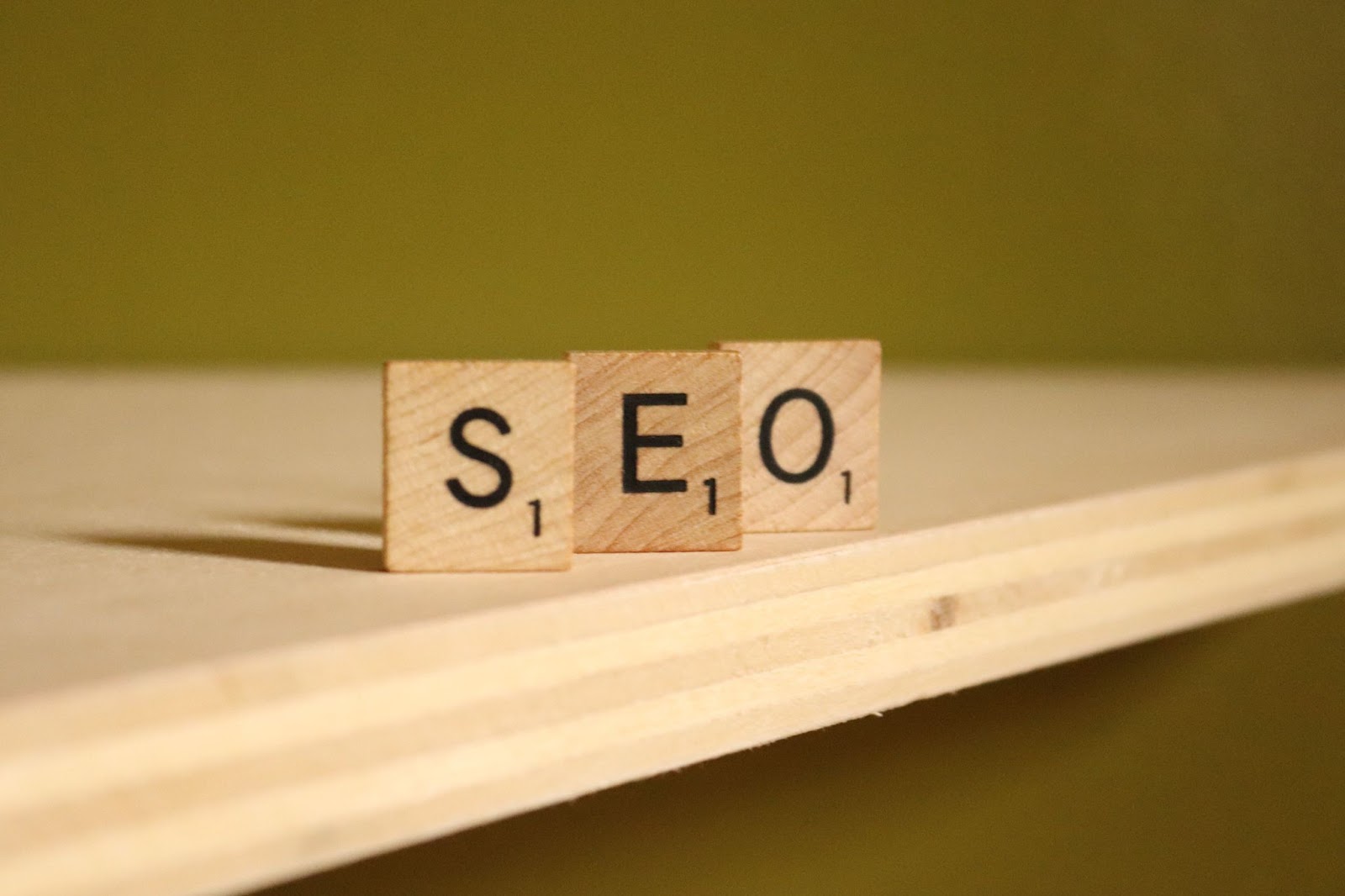Three wooden letters displaying SEO on a wooden table