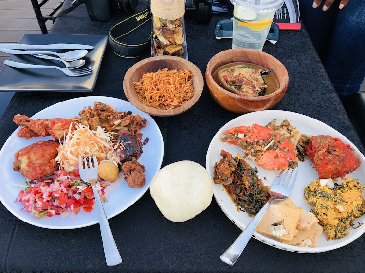 From left to right, stewed chicken, ponmo, mackerel, puff puffs, kachumbari and salad. Bowl of jollof rice, bowl of catfish pepper soup, swallow in the middle. Crab leg, pepper tilapia, egusi moi moi and efo riro.