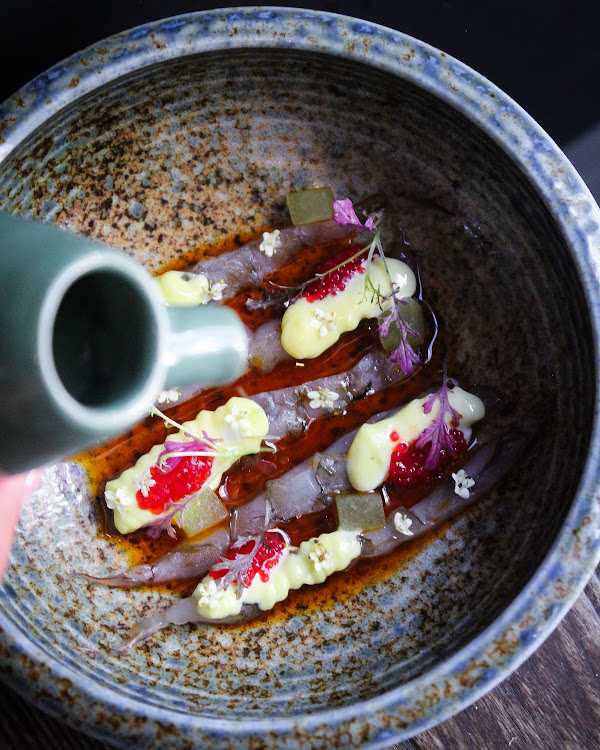 Shrimp crudo with melon gazpacho, ancho oil, smoked pepper and chive flowers.