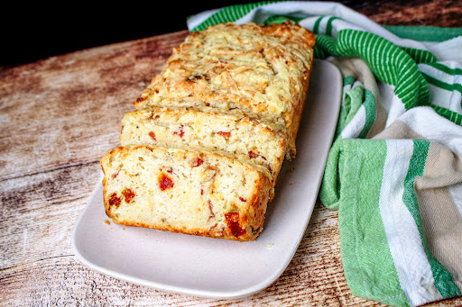Slices of Beer Bread With Bacon, Sun-Dried Tomato, and Cheddar on a platter.