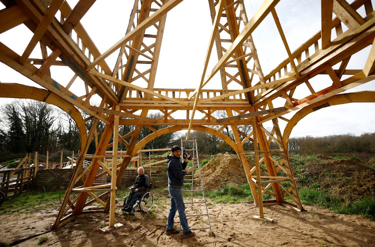 French carpenter Frederic Malmezac and Sylvain Bouchard, a sports enthusiast with disability, work on a 16-meter replica of the Eiffel Tower built from recycled wood which they hope to display along the path of the Olympic torch relay and on Olympic sites for the Paris 2024 Olympic and Paralympic Games, in La Chevroliere, near Nantes, France, February 19, 2024.