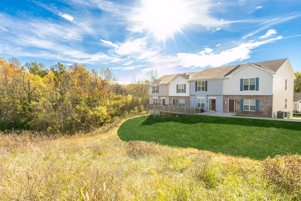 A row of townhomes with varying exterior colors and a large grass area in front