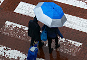 Pedestrians brave the rain crossing Cavendish Street in Claremont, Cape Town on Cape Town June 13 2022. The worst affected areas are informal settlements in Khayelitsha, Ottery, Langa, Strand, Philippi, Gugulethu, Delft and Vrygrond.