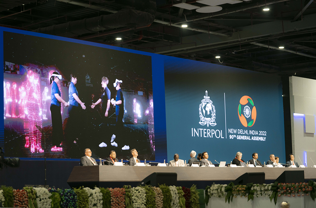 Panel of Interpol employees in front of big screen showing people using VR