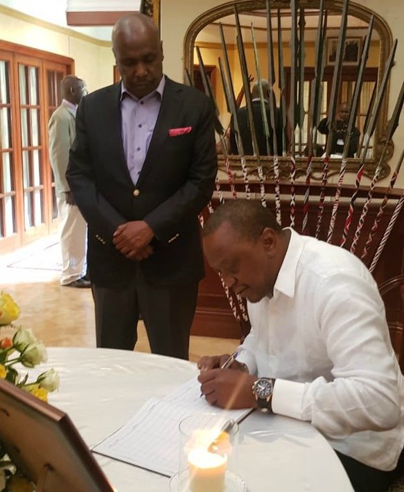 President Uhuru Kenyatta signs the condolence book as Baringo Senator Gideon Moi looks on.