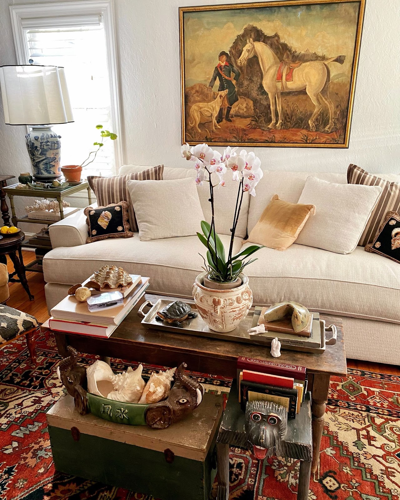 An oversized equestrian painting hangs above a creamy white sofa