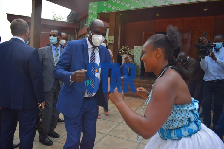 IEBC Chairperson Wafula Chebukati shares a light moment with a Giriama traditional dancer as she makes her way to the Bomas of Kenya for the IEBC Strategic plan 2020-2024 launch OK June 15, 2021.