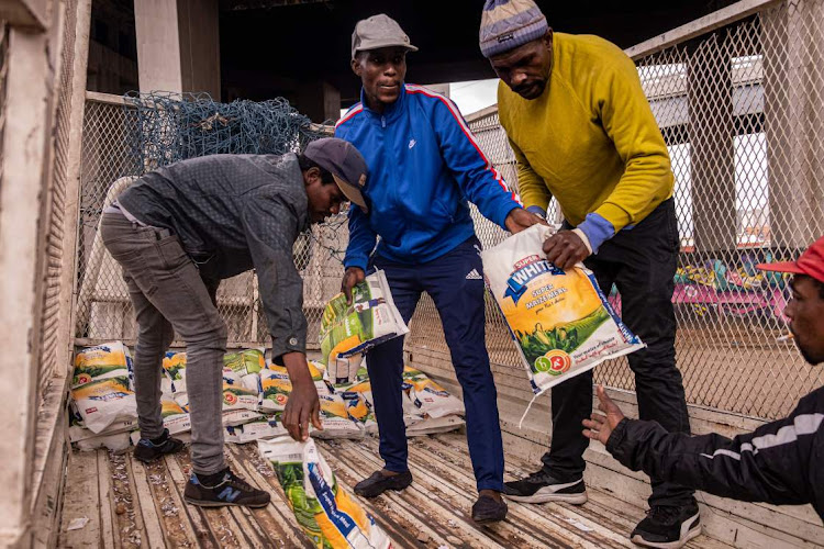 Residents of the Bekezela informal settlement receive a maize meal donation from Remade Recycling in Newtown, Johannesburg. Picture: Emmanuel Croset / AFP