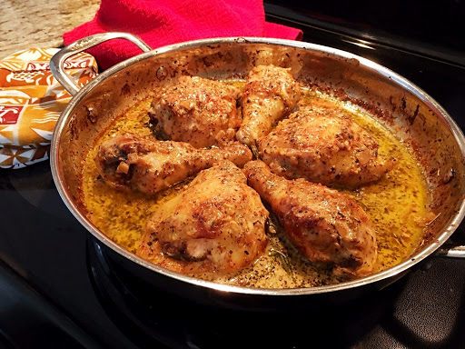 Three cooked chicken drumsticks and three cooked chicken thighs in a large saucepan in a creamy sauce.