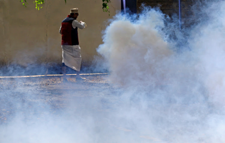 A pro-Palestinian demonstrator runs past tear gas lobbed by riot policemen to disperse a protest following a flare-up of Israeli-Palestinian violence, in Nairobi, Kenya May 13, 2021.