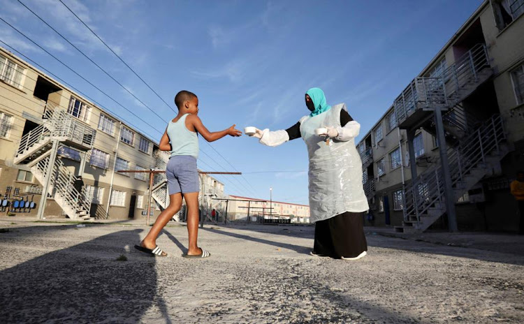 A boy receives food from a member of Moms Who Care in Hanover Park.