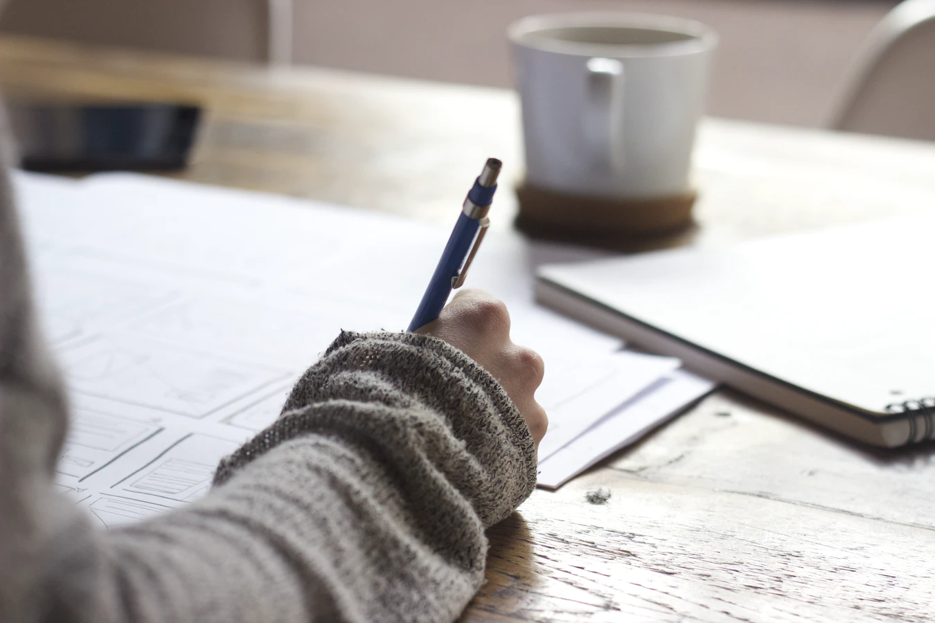 a person holding a pen over a table filled with notes