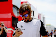 MONTMELO, SPAIN - MAY 07:  Fernando Alonso of Spain and McLaren Honda looks at his phone as he walks through the paddock during previews to the Spanish Formula One Grand Prix at Circuit de Catalunya on May 7, 2015 in Montmelo, Spain.  (Photo by Clive Mason/Getty Images)
