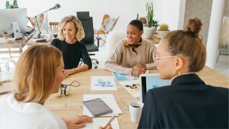 4 vrouwen houden een teamvergadering aan een tafel in een kantoor