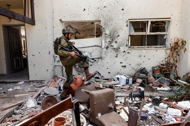 An Israeli soldier steps over personal belongings near a home in in Kibbutz Be'eri in southern Israel. Picture: AMIR COHEN/REUTERS